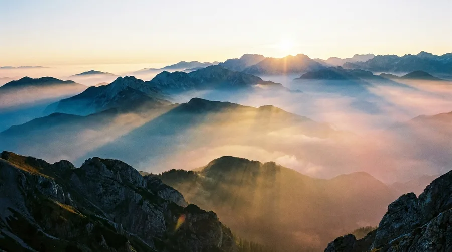 Weites Bergpanorama mit schneebedeckten Gipfeln bei Sonnenaufgang als Leuchtbild-Motiv